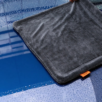 ACP11389 - Hand holding up the corner of a gray Spigen microfiber towel over a wet, water-splashed surface