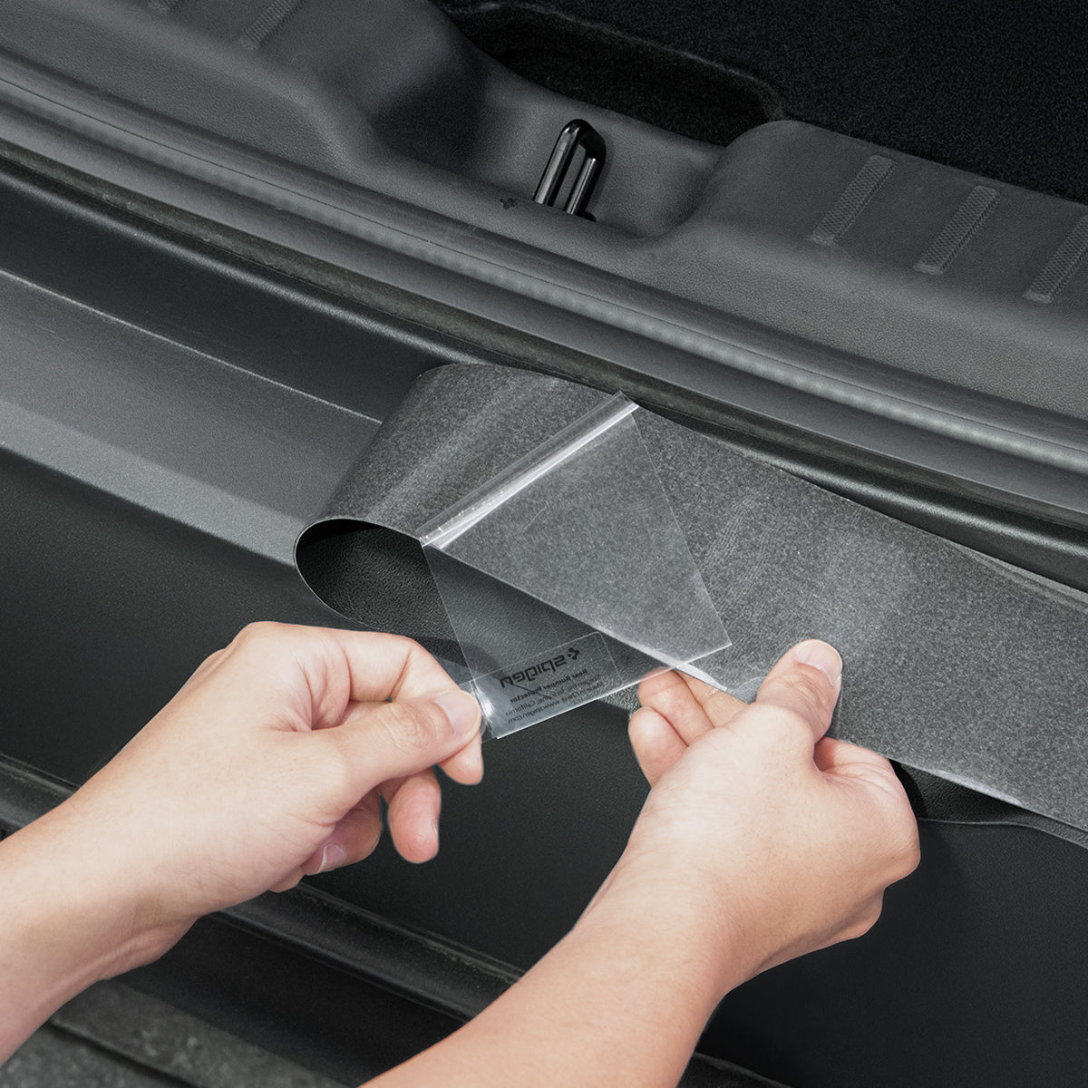 ACP10618 - Model Y Juniper (2025+) Rear Bumper Guard | TG200-YJ showing a person slowly peeling the adhesive protective film off the rear bumper guard