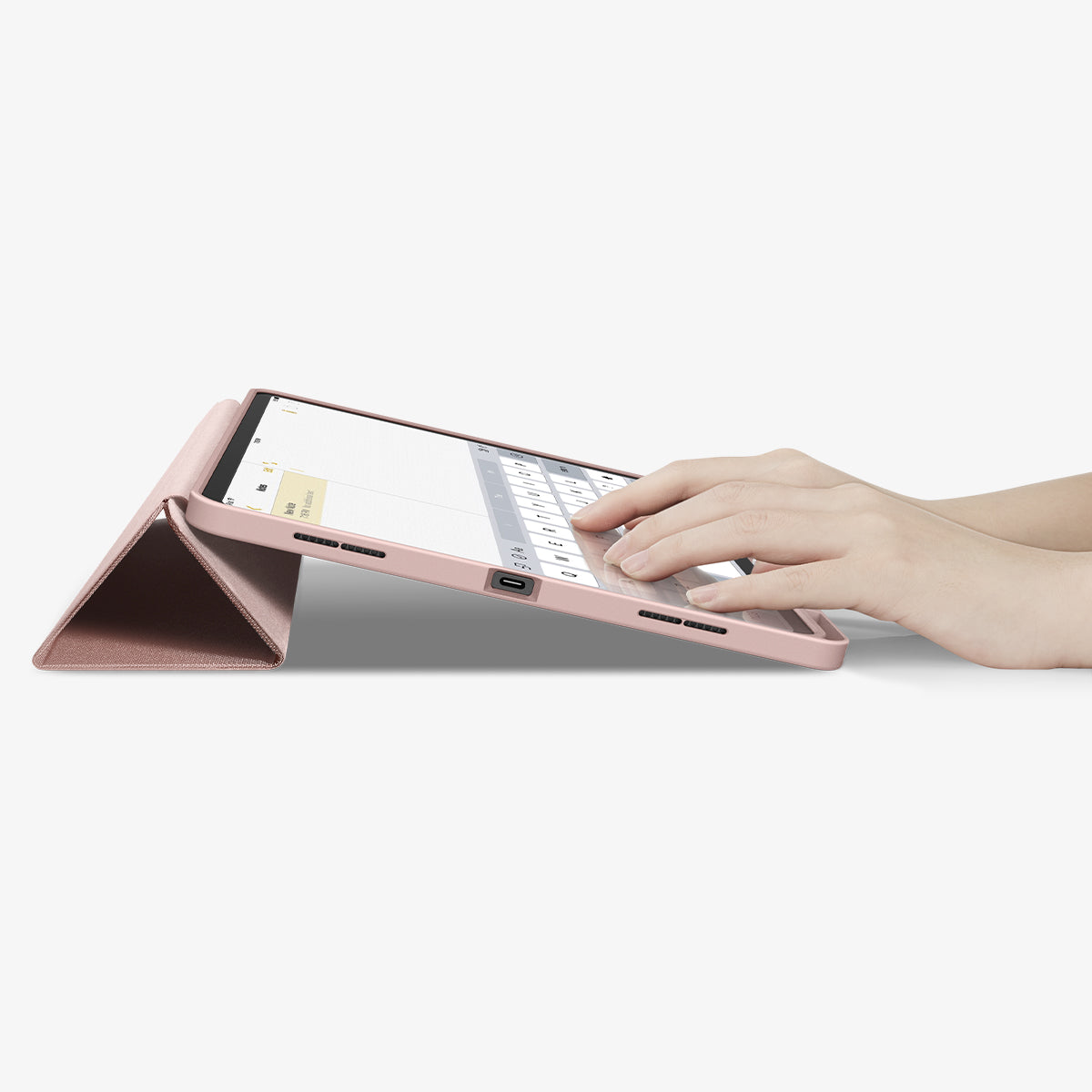 ACS07673 - iPad Air 12.9-inch Case Urban Fit in Rose Gold showing the partial front with a hand typing on the device with a folded front cover propped up as a stand