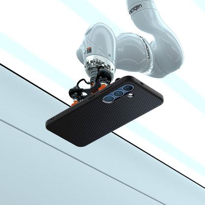ACS08979 - Galaxy S25 Plus Case Liquid Air in Matte Black showing the robotic arm holding the device in an elevated horizontal position, angled slightly upward. Showing the device back facing outward, revealing its camera module. The robotic arm is positioned above a clean, structured background with defined panels